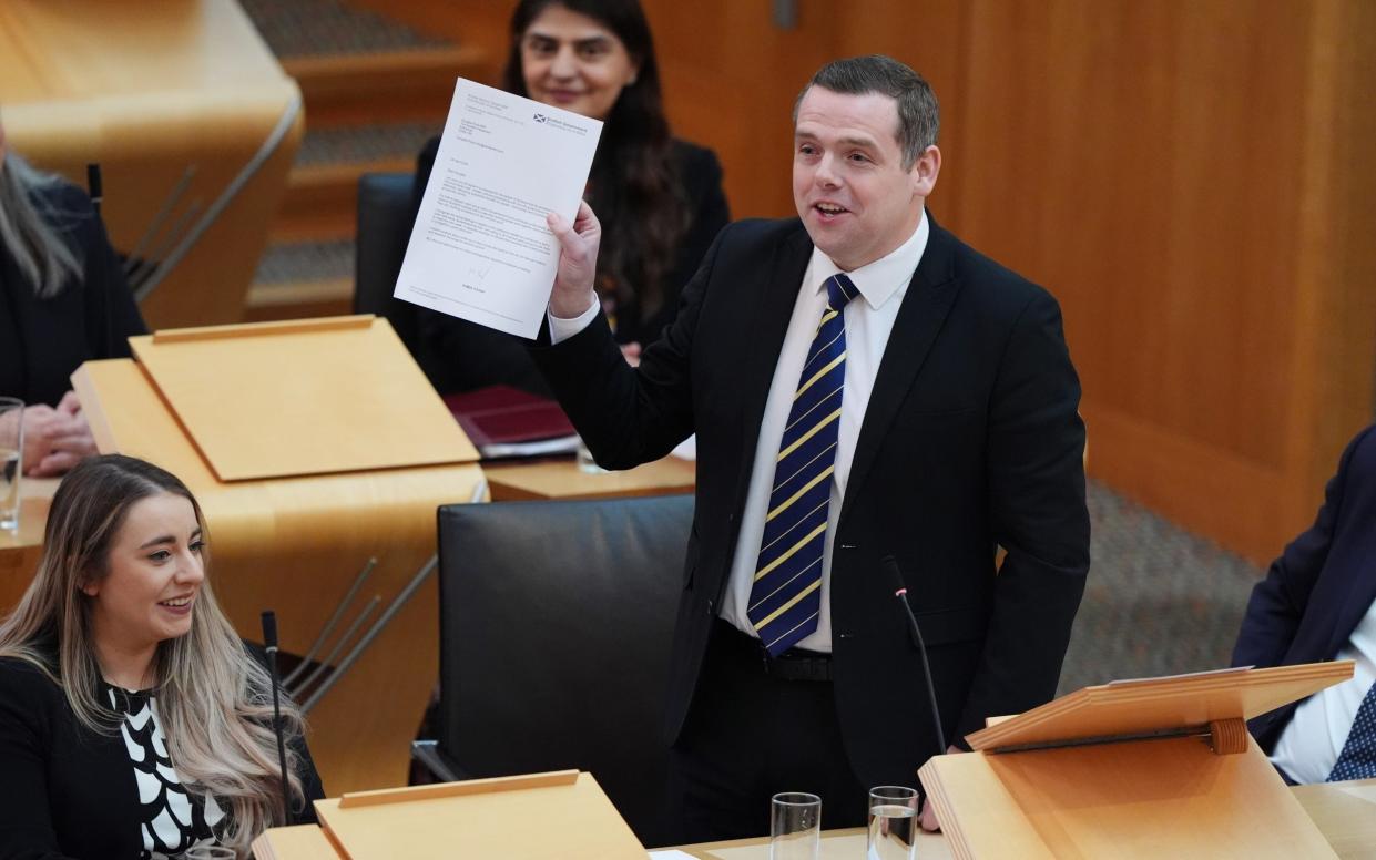 Douglas Ross, the Scottish Tory leader, holds up a letter written to him by Humza Yousaf during FMQs at Holyrood