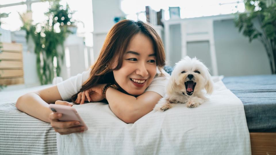 Woman lying on bed with Maltese dog beside her