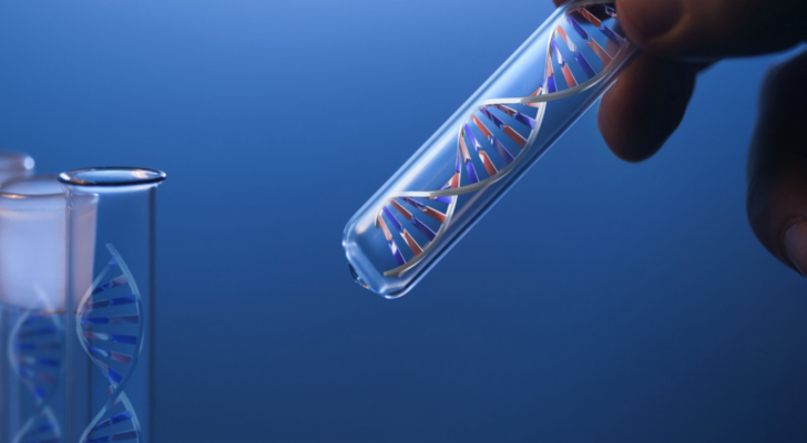 DNA molecule in glass tube in hand of scientist on blue. Invitae does genetic testing. NVTA stock