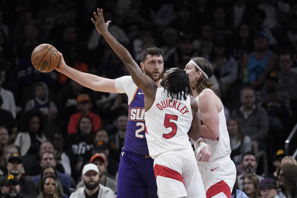 Phoenix Suns center Jusuf Nurkic (20) keeps the ball away from Toronto Raptors guard Immanuel Quickley (5) and Toronto Raptors forward Kelly Olynyk (41) during the first half of an NBA basketball game in Phoenix, Thursday, March. 7, 2024. (AP Photo/Darryl Webb)