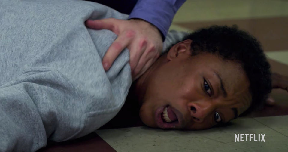 A woman is pinned to the ground by a prison officer