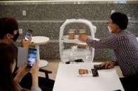 A robot that takes orders, makes coffee and brings the drinks straight to customers delivers an order in a cafe in Daejeon