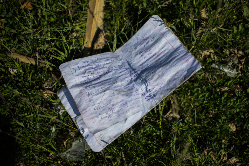 A student notebook lies on the ground next to a school destroyed in a Russian bombing in Bakhmut, eastern Ukraine, Tuesday, May 24, 2022. The town of Bakhmut has been coming under increasing artillery strikes, particularly over the last week, as Russian forces try to press forward to encircle the city of Sieverodonetsk to the northeast. (AP Photo/Francisco Seco)