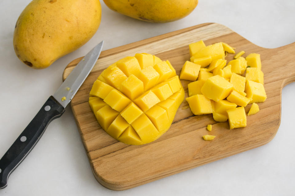 Diced mango with whole mangoes in the background