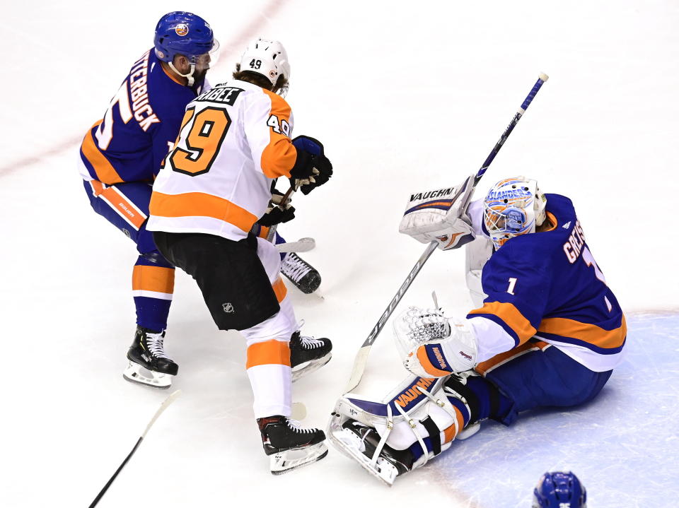 Philadelphia Flyers left wing Joel Farabee (49) and New York Islanders right wing Cal Clutterbuck (15) battle for position in front of Islanders goaltender Thomas Greiss (1) during the first period of an NHL hockey second-round playoff series, Sunday, Aug. 30, 2020, in Toronto. (Frank Gunn/The Canadian Press via AP)