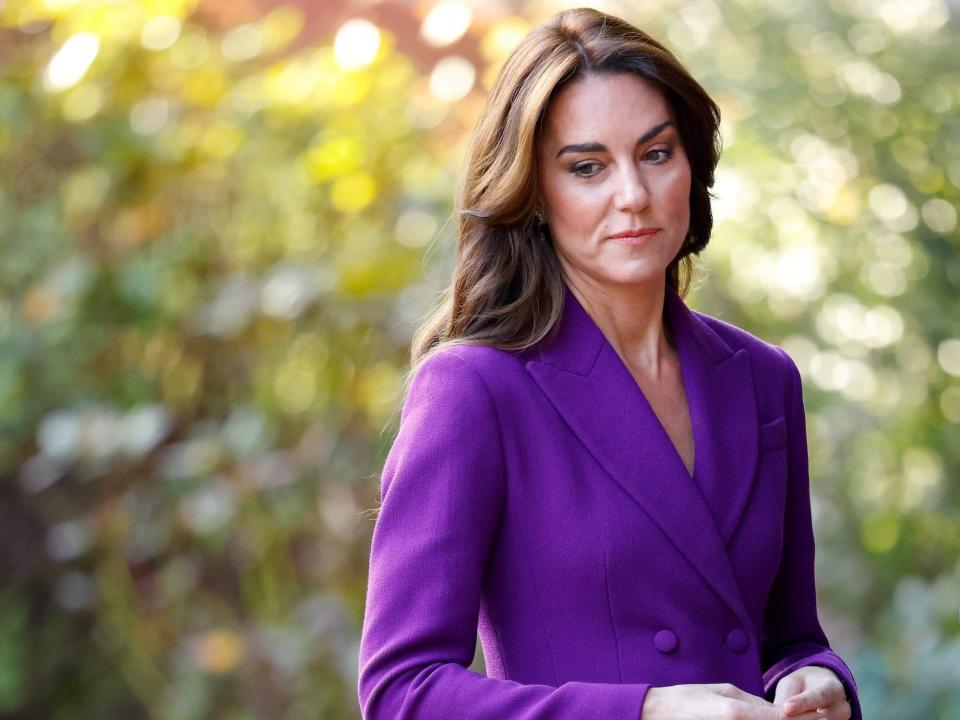 Kate Middleton looks down in a purple suit.