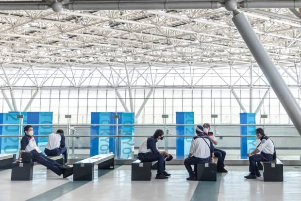 Security guards sit in the IBC/MPC Tokyo International Exhibition Centre ahead of the 2020 Olympic Games on July 20 in Tokyo. Set to begin on Friday, the event was touted as safe and secure by organizers, but has so far been plagued by COVID-19 infections. (Maja Hitij/Getty Images - image credit)