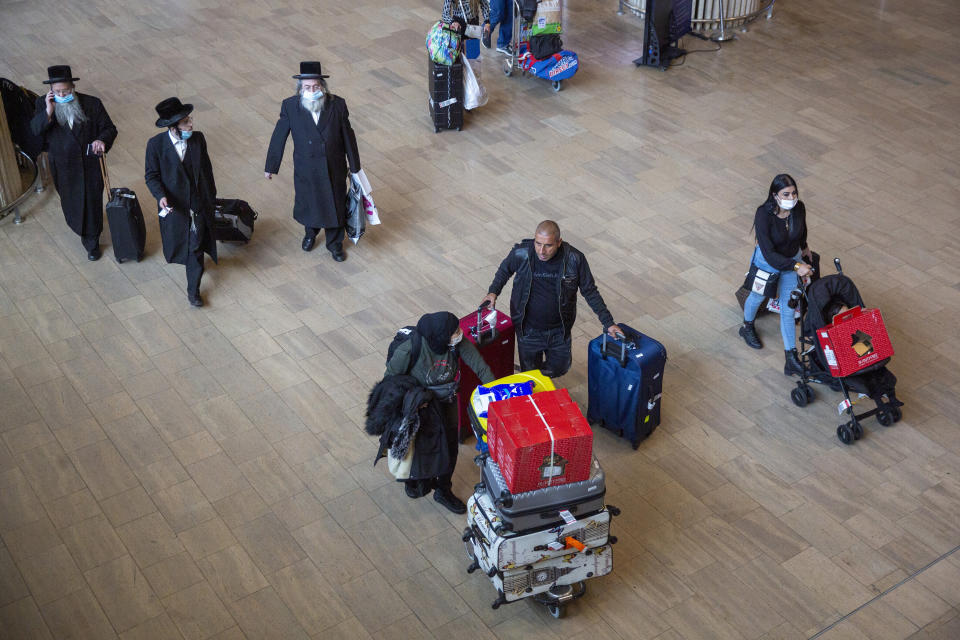 People wearing protective face masks arrive at the Ben Gurion Airport near Tel Aviv, Israel, Monday, Nov. 1, 2021. Israel on Monday began welcoming individual tourists for the first time since the onset of the coronavirus pandemic. (AP Photo/Ariel Schalit)