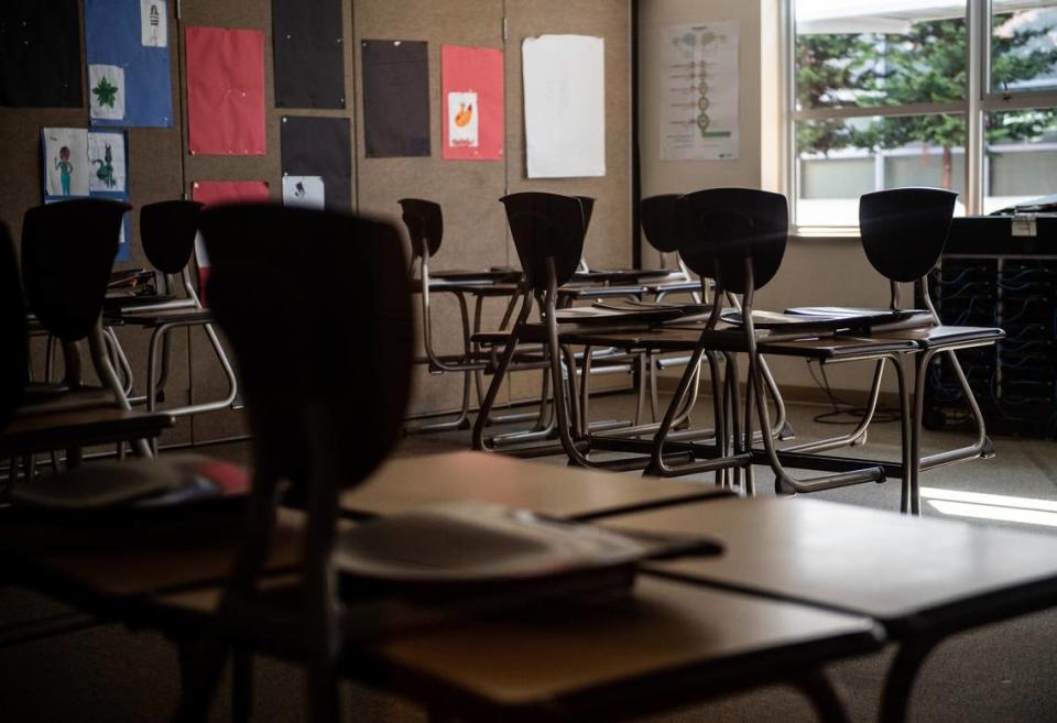 Chairs are stacked on desks in an empty classroom.