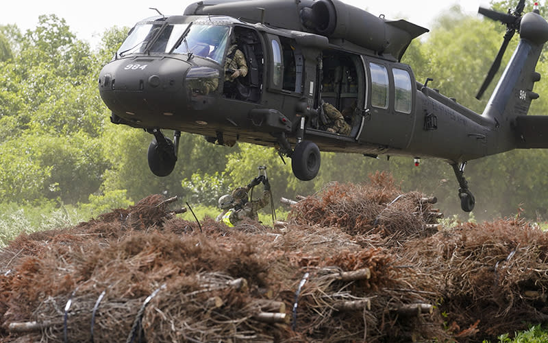 A helicopter hovers over bundles of Christmas trees