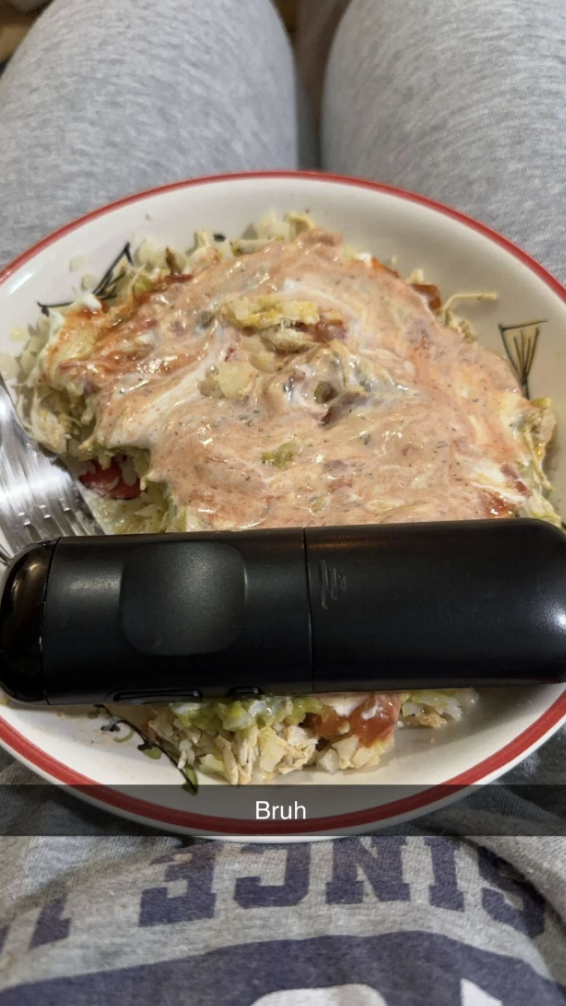 Remote control on a plate of shredded cabbage covered in sauce with a fork beside it; the caption reads, "Bruh"