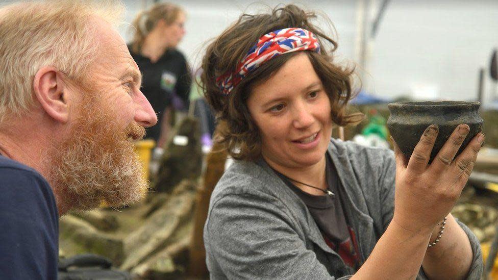 Two archaeologists examining a Bronze Age bowl at the Must Farm excavation