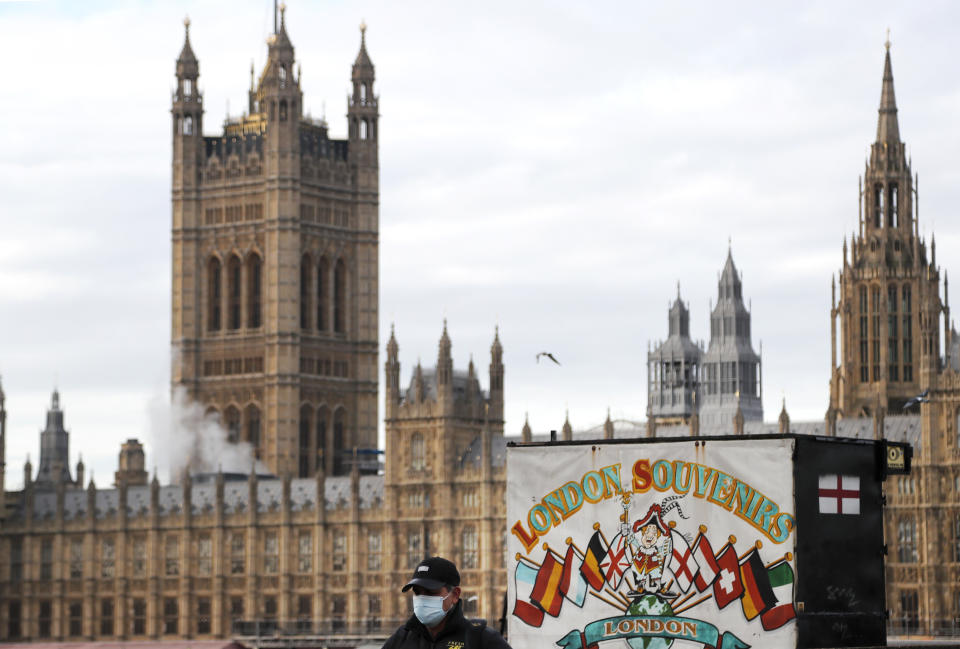A man walks past a souvenir shop opposite the Houses of Parliament during the debate in the House of Commons on the EU (Future Relationship) Bill in London, Wednesday, Dec. 30, 2020. The European Union's top officials have formally signed the post-Brexit trade deal with the United Kingdom, as lawmakers in London get set to vote on the agreement. (AP Photo/Frank Augstein)