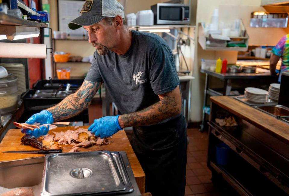 Andrew Potts breaks apart a pork shoulder in the kitchen at Smokey Joe’s Barbecue on Monday, October 9, 2023 in Lexington, N.C.