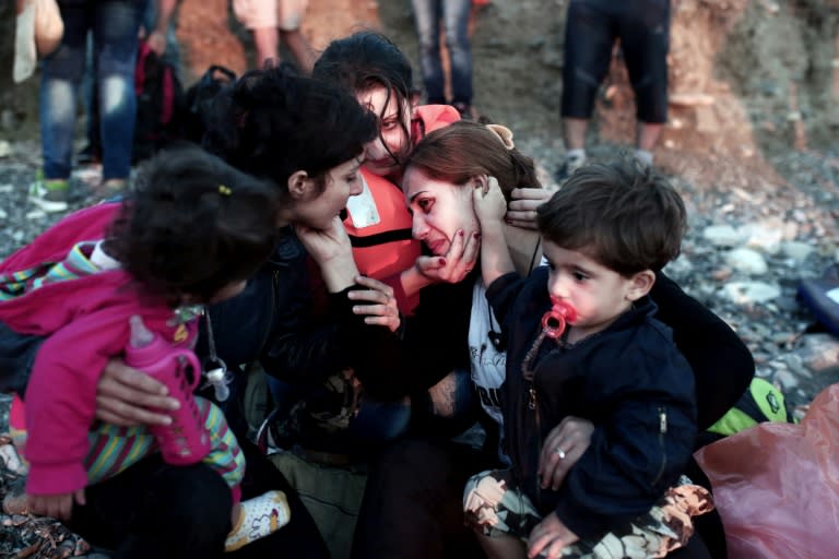 Migrant women carrying children comfort each other upon reaching the Greek island of Kos after crossing a part of the Aegean Sea between Turkey and Greece on August 13, 2015