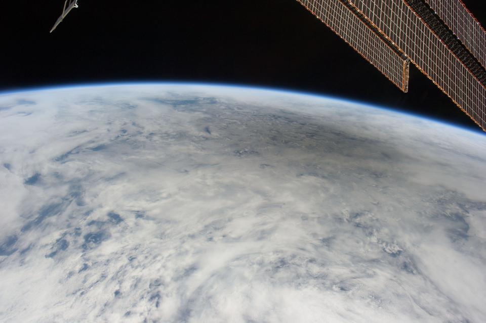 the fuzzy circular shadow of the moon appears on white clouds that cover the curvature of earth as seen from space