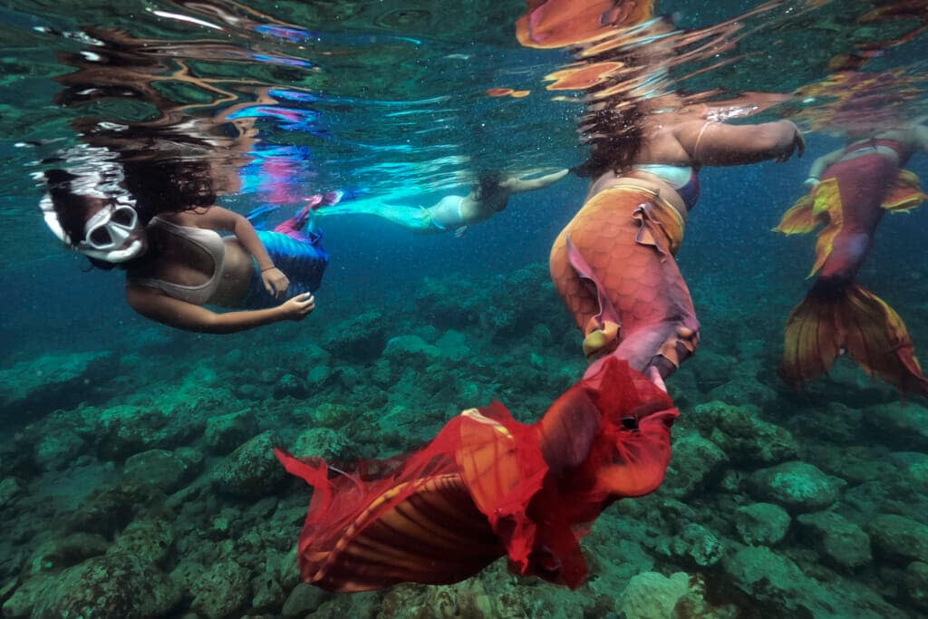 Filipina Jennica Secuya, left, swims with other students during a mermaiding class in Mabini, Batangas province, Philippines on Sunday, May 22, 2022. It is also a world, merfolk say, where you can be whoever and whatever you want. (AP Photo/Aaron Favila)