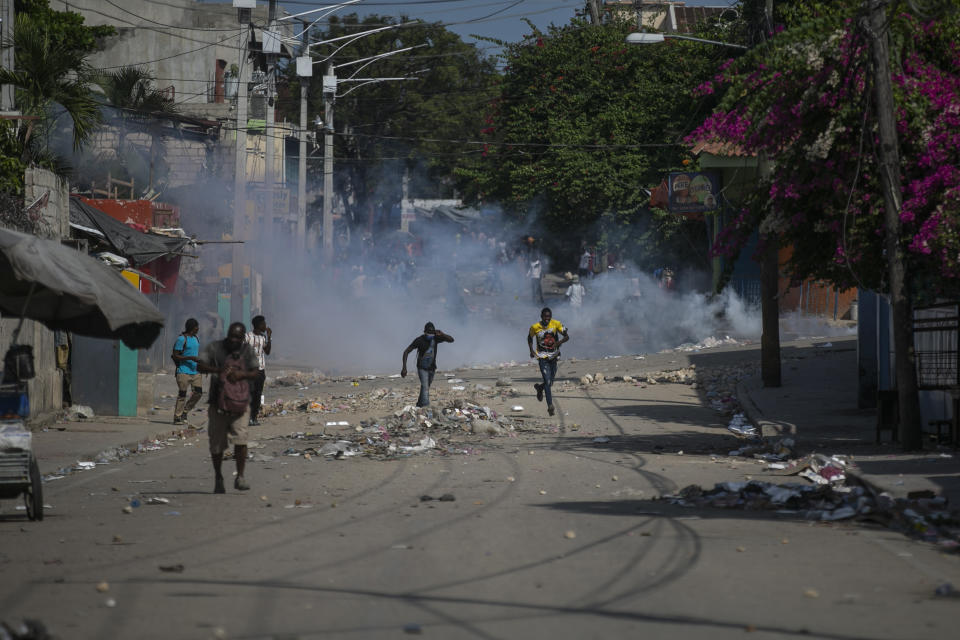 Manifestantes corren después de que la policía arrojara gases lacrimógenos durante una protesta para exigir la renuncia del primer ministro Ariel Henry, el lunes 3 de octubre de 2022, en la zona de Petion-Ville, en Puerto Príncipe, Haití. (AP Foto/Odelyn Joseph)