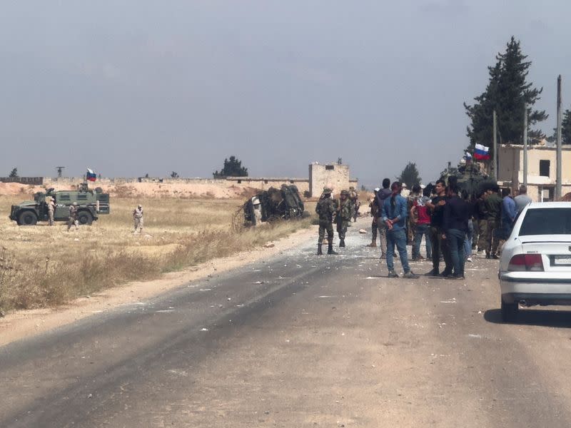 Russian military vehicles are parked near an overturned military vehicle, following an attack that the Syrian Observatory for Human Rights said was caused by Turkish shelling near Tal Rifat