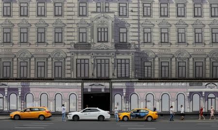 People walk past a building decorated with a giant banner in Moscow, Russia July 1, 2018. REUTERS/Gleb Garanich