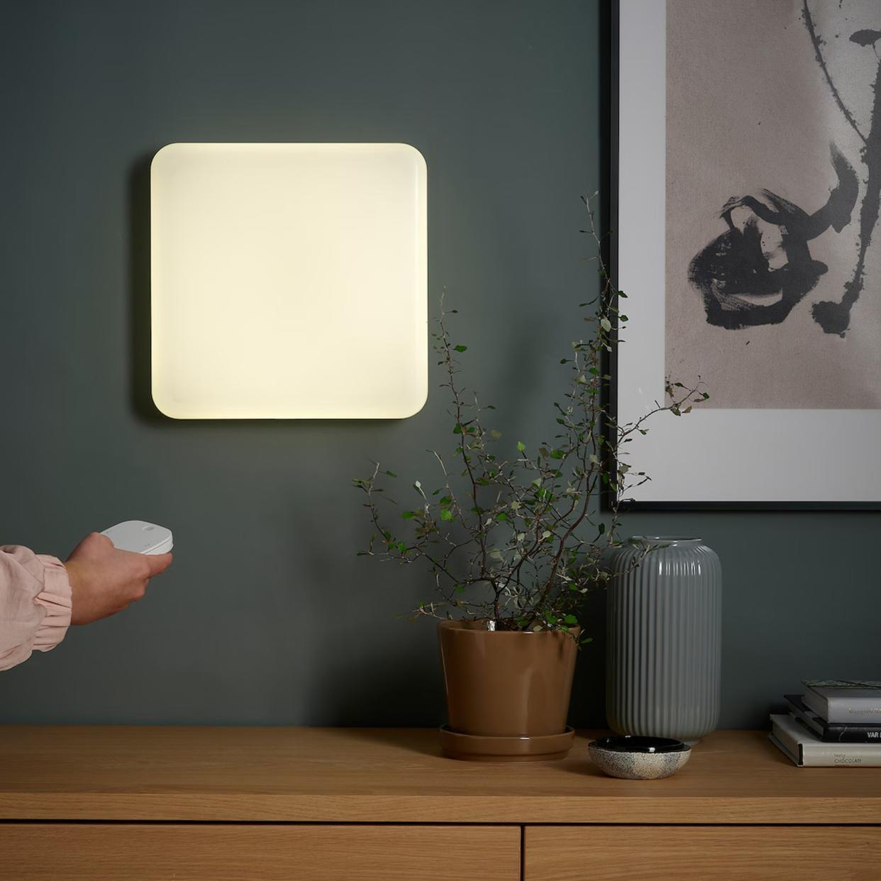  IKEA JETSTRÖM LED wall light panel on a wall, someone turning it on using a remote control. 