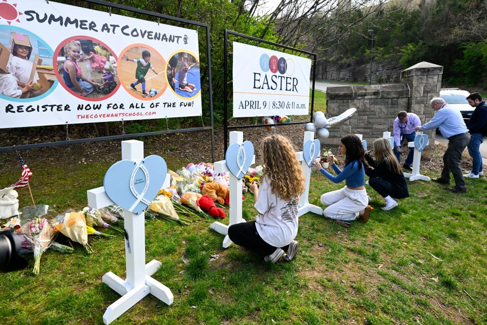 Mourners write messages on memorial crosses at an entry to The Covenant School in Nashville, Tenn., on March 28, 2023.