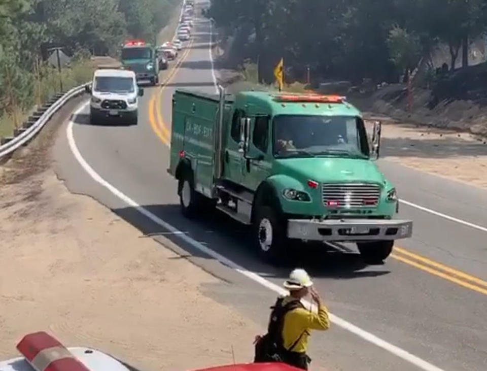 This image taken from video and provided by the Orange County Fire Authority shows a firefighter saluting as a procession carrying a fallen firefighter passes by at the El Dorado Fire in Southern California, September 18, 2020.  / Credit: Orange County Fire Authority via AP