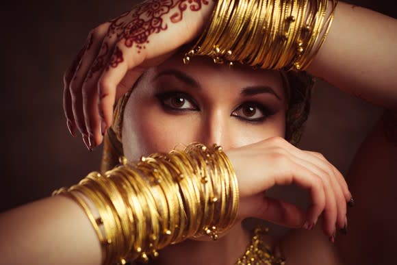 A woman hiding her face behind arms covered with gold bangles