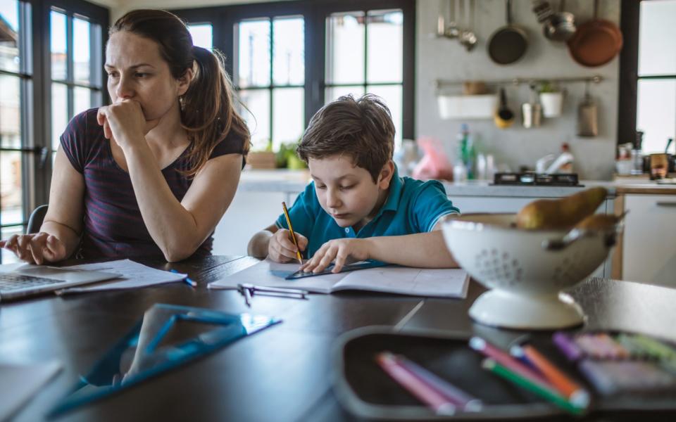 Mother working at the kitchen table with child - Milos Stankovic