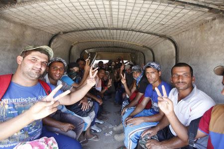 Shi'ite volunteers, who have joined the Iraqi army to fight against militants of the Islamic State, formerly known as the Islamic State in Iraq and the Levant (ISIL), flash signs to the camera from inside a truck in Baghdad July 9, 2014. REUTERS/Ahmed Saad