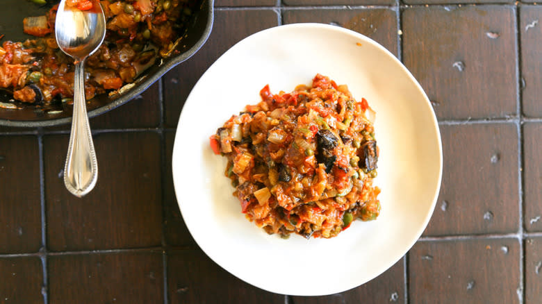 Olives, onion, and tomato mixture in serving dish and plate