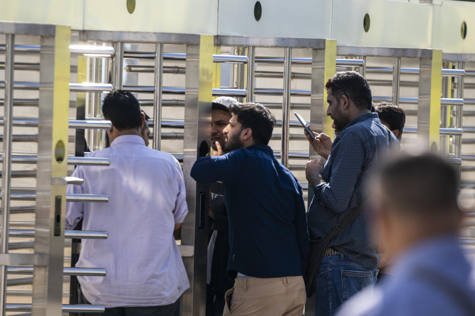 Sohaib Asghar, center, waits at the turnstiles and speaks with survivors of a deadly migrant boat sinking at a migrant camp in Malakasa north of Athens, on Monday, June 19, 2023. Hundreds of migrants are believed to be missing after a fishing trawler sank off southern Greece last week. (AP Photo/Petros Giannakouris)