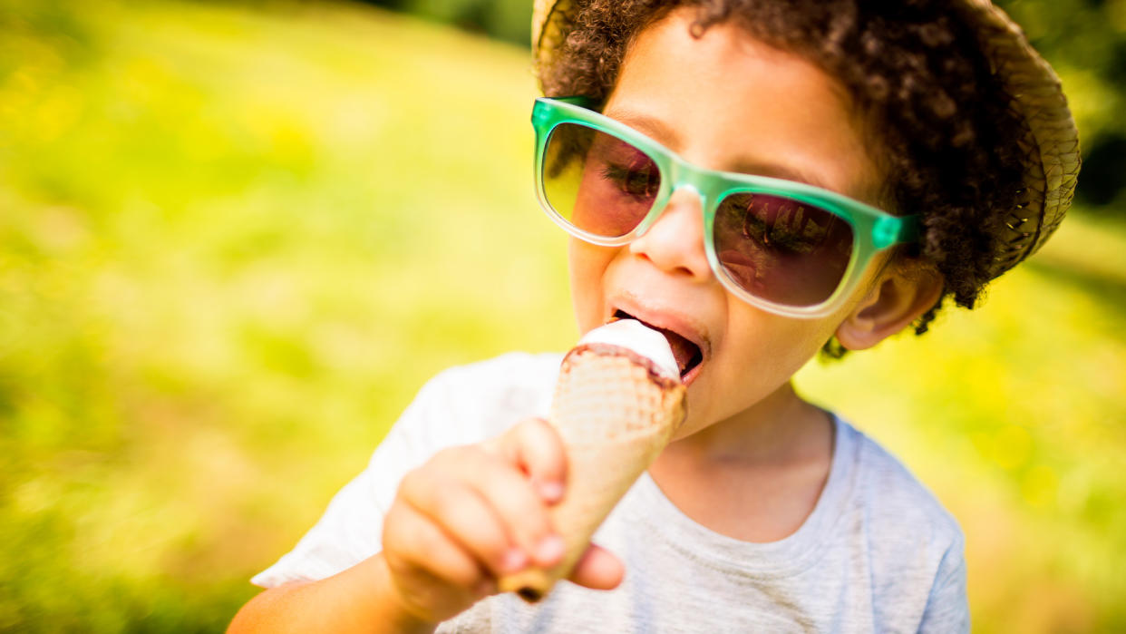  Little boy licking ice cream in a cone during summertime. 