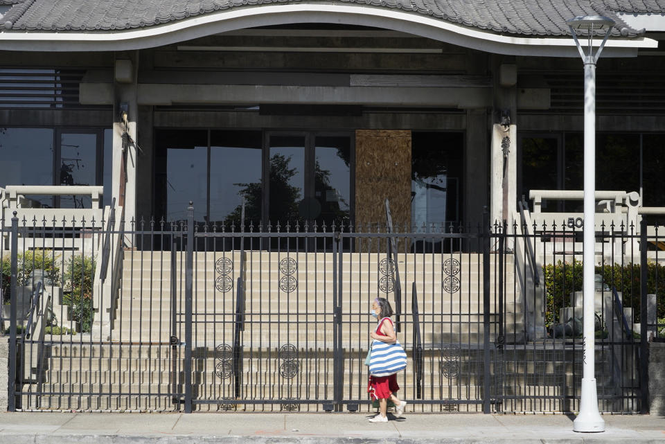 A pedestrian walks past the closed Higashi Honganji Buddhist Temple in Los Angeles Saturday, Feb. 27, 2021. Authorities are investigating the vandalism and fire at the Buddhist temple in the Little Tokyo section of downtown Los Angeles. The incident Thursday night occurred as hate crimes against Asian Americans are increasing nationwide. However, police said it was too early to label Thursday night's vandalism at the Higashi Honganji Buddhist Temple a hate crime. (AP Photo/Damian Dovarganes)