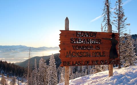 Jackson Hole "last of the old West" sign with snowy mountains in the background