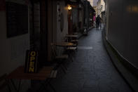 A man walks with his bike through a narrow alley lined with restaurants in Nara, Japan, Tuesday, March 17, 2020. (AP Photo/Jae C. Hong)