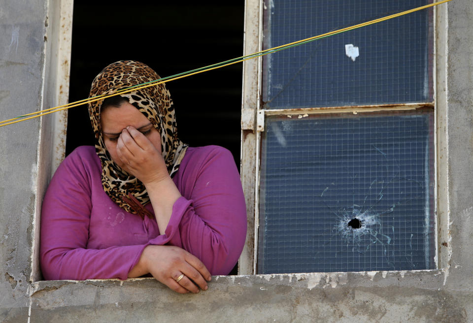 A Lebanese woman reacts after her home was damaged from a bullet during clashes that erupted between supporters and opponents of Syrian President Bashar Assad, near the Sunni neighborhood of Tariq Jadideh, in Beirut, Lebanon, Sunday, March 23, 2014. Syria-related clashes between supporters and opponents of Syrian President Bashar Assad have prompted Lebanese troops to deploy to a Beirut neighborhood to calm tensions. The Army deployment came after rival Sunni gunmen exchanged gunfire and rocket-propelled-grenades for several hours in the area, in the worst fighting in the Lebanese capital in nearly two years. (AP Photo/Hussein Malla)