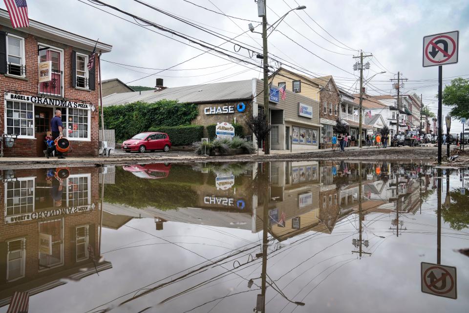 Residents, journalists, and emergency service workers walk around a flooded Main Street, Monday (AP)