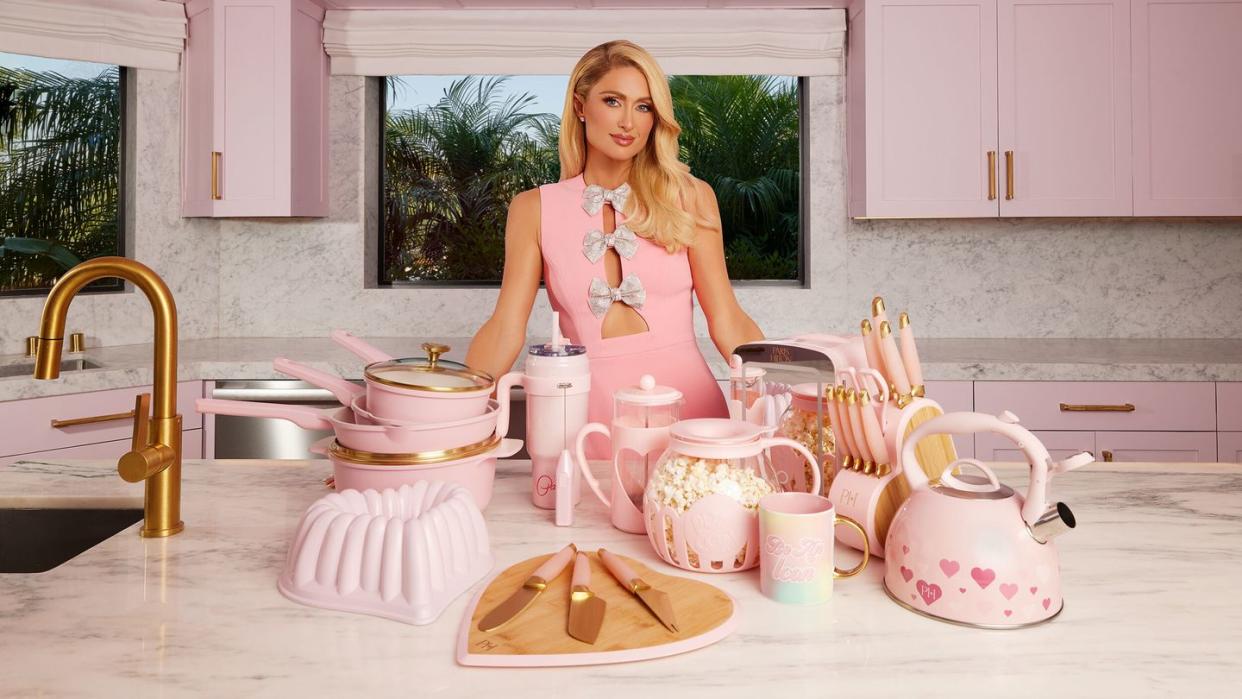 paris hilton standing behind a table with a cake and cups