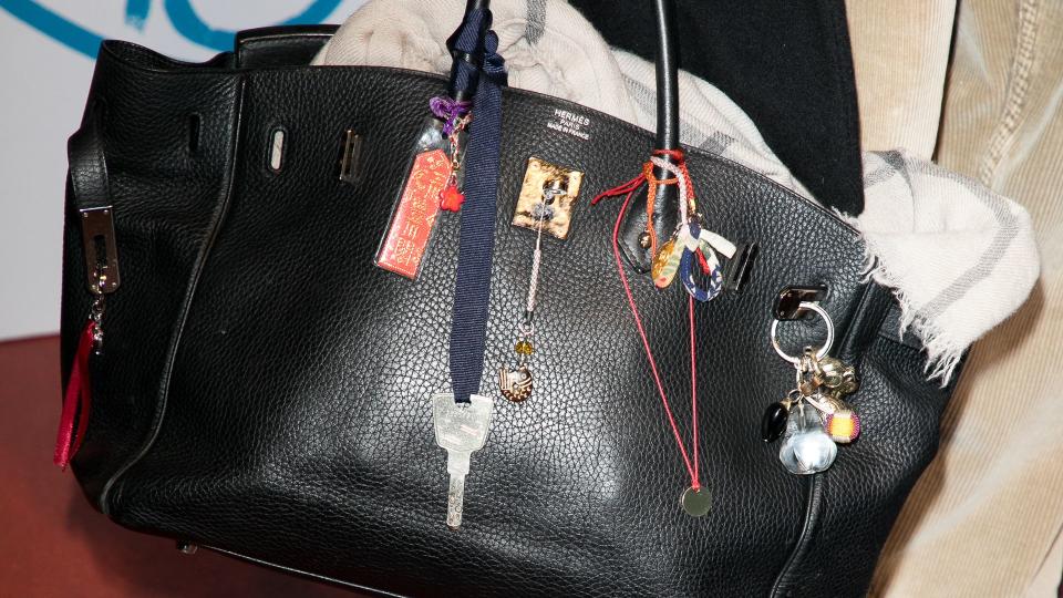 A close up of Jane Birkin's personal Birkin bag adorned with trinkets and keepsakes