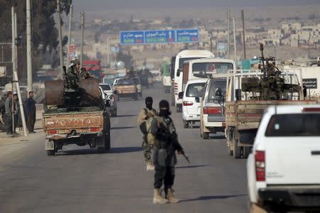 Fighters from a coalition of rebel groups called "Jaish al Fateh", also known as "Army of Fatah" (Conquest Army), escort a convoy of Syrian Arab Red Crescent ambulances and buses evacuating fighters and civilians from the two besieged Shi'ite towns of al-Foua and Kefraya as heading towards the Syrian-Turkish border crossing of Bab al-Hawa, to cross to Turkey December 28, 2015. REUTERS/Khalil Ashawi