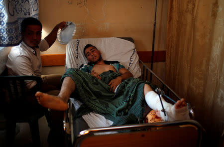 A man cools off an injured Palestinian as he lies on a bed at a hospital in Gaza City May 15, 2018. REUTERS/Mohammed Salem