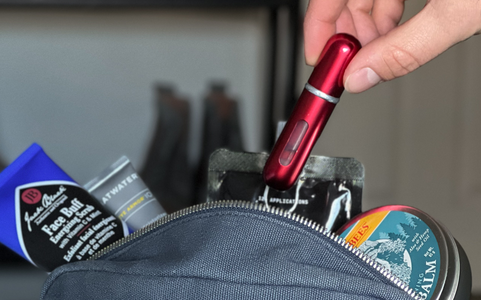 placing a red travalo atomizer into our dopp kit before traveling