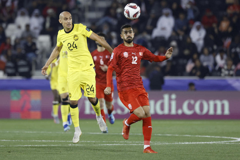 Malaysia's midfielder Natxo Insa (left) challenges for the ball with Bahrain's midfielder Ali Hassan in their 2023 AFC Asian Cup match.