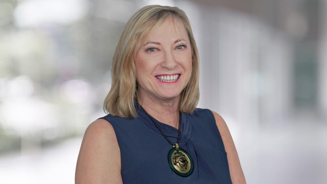 Managing Director of investment bank Cowen Helane Becker wears a blue top with a large green necklace