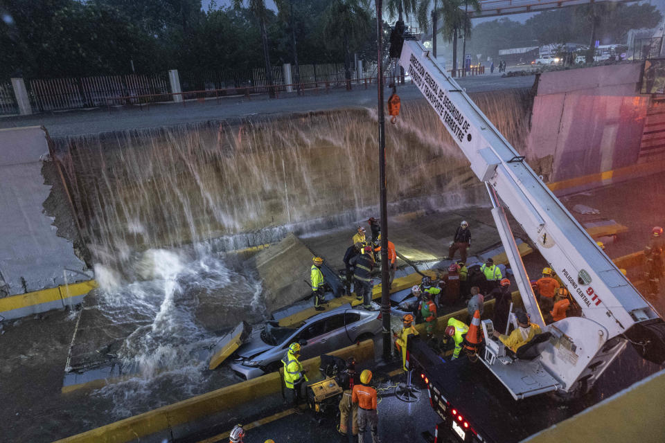 Rescue teams work at the place where a wall collapsed at the entrance of a tunnel in Santo Domingo, Dominican Republic, Saturday, Nov. 18, 2023. According to Civil Defense at least 9 people were killed when the wall fell down due to heavy rains. ( AP Photo/Eddy Vittini)