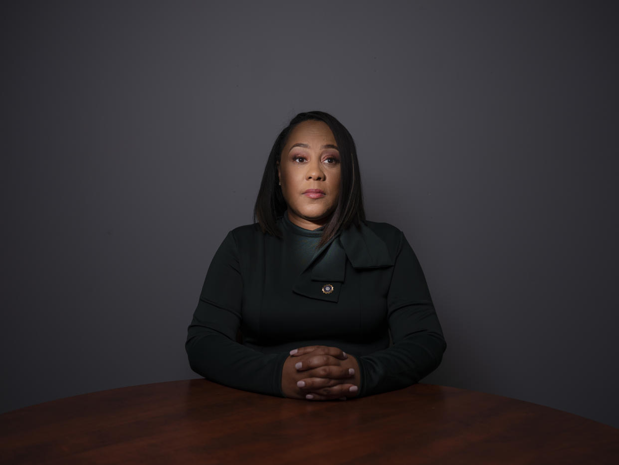 Fulton County District Attorney Fani Willis sits at a desk with her hands clasped.