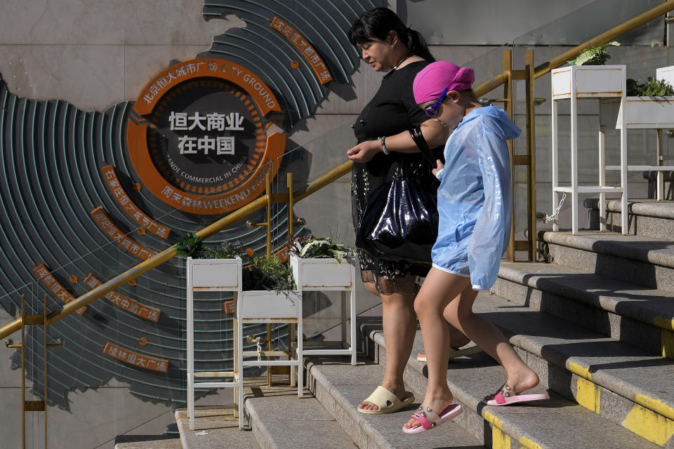 A woman and a child walk by a map showing Evergrande development projects in China at an Evergrande city plaza in Beijing on Sept. 21, 2021. Shares were mostly lower in Asia on Monday after troubled Chinese property developer Evergrande warned late Friday it may run out of money. (AP Photo/Andy Wong)