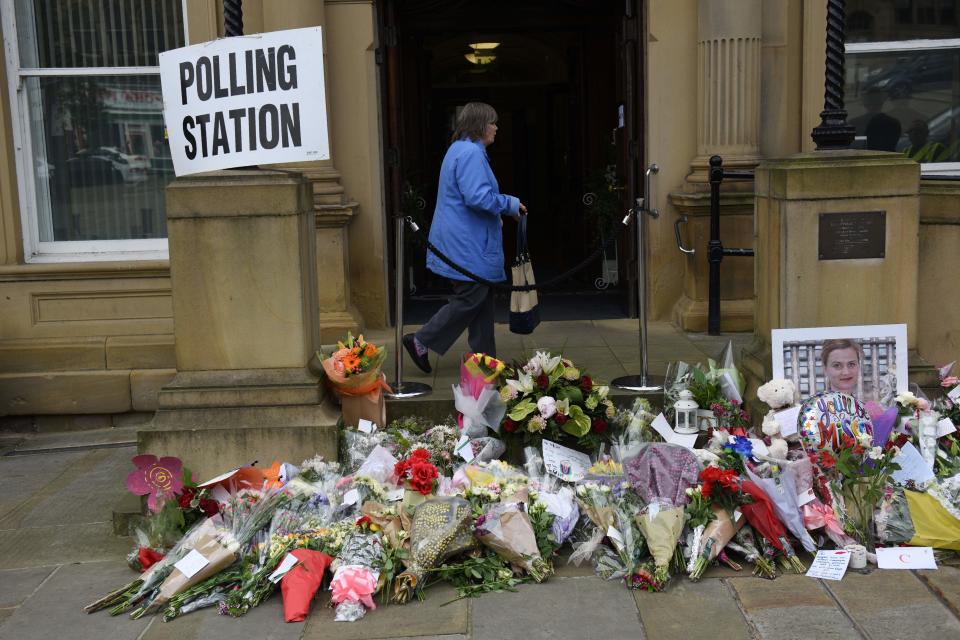 A woman passes floral tributes to murdered MP Jo Cox outside Batley Town Hall as she arrives to vote in the EU referendum in Batley, northern England on June 23, 2016.