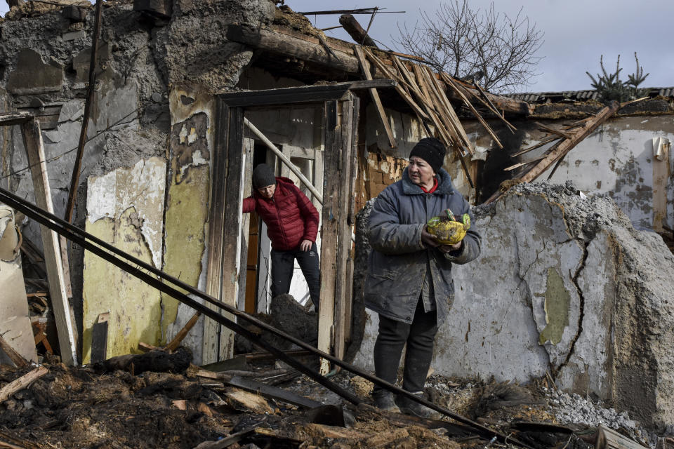 Inna, 71, holds food items found as she stands outside her house which was destroyed by a Russian drone attack in a residential neighborhood, in Zaporizhzhia, Ukraine, on Thursday, March 28, 2024. (AP Photo/Andriy Andriyenko)